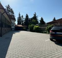 NA PREDAJ hotel s reštauráciou - Parkovisko pre hotely a penzióny s autom, stromami a budovou v pozadí.