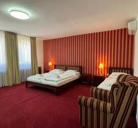 NA PREDAJ hotel s reštauráciou - Hotelová izba s červenými závesmi, dvojposteľou a kreslom. Hotely a penzióny.