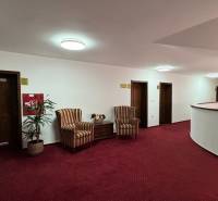 NA PREDAJ hotel s reštauráciou - Chodba s červeným kobercom, kreslami a izbami vo vnútri hotela alebo penziónu.