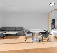 REZERVOVANÉ Krásny 4i RD 105m2, smart systém, záhrada, úplne nový - Obývacia izba s kuchyňou v rodinnom dome, vybavená šedou sedačkou a jedálenským stolom.