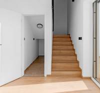 REZERVOVANÉ Krásny 4i RD 105m2, smart systém, záhrada, úplne nový - Interiér rodinného domu s dreveným schodiskom, bielymi stenami a veľkým oknom.