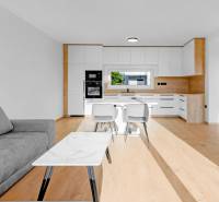 REZERVOVANÉ Krásny 4i RD 105m2, smart systém, záhrada, úplne nový - Interiér Rodinného domu so svetlou kuchyňou, obývačkou, sivým gaučom a drevenou podlahou.