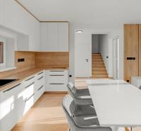 REZERVOVANÉ Krásny 4i RD 105m2, smart systém, záhrada, úplne nový - Kuchyňa v rodinnom dome so svetlým nábytkom, dreveným obložením a schodiskom.