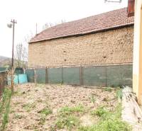  4i RD s pozemkom 269m2, Kálnica - NMnV - Vonkajší pohľad na kamennú stenu, plot a záhradu pri rodinnom dome.