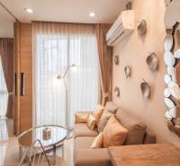 1 IZBOVÝ APARTMÁN A (1 SPÁLŇA + 1 OBÝV. IZBA) CITY GARDEN OLYMPUS  - Obývacia izba 2-izbového bytu so svetlým interiérom, zrkadlami a dekoratívnymi vankúšmi.