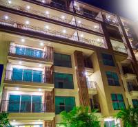 CITY GARDEN TROPICANA PATTAYA - Výstavba bytov v Pattayi s osvetlenou fasádou a množstvom balkónov v noci.