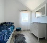 Šolta - nádherný zariadený apartmán s výhľadom na more - Spálňa v rekreačnom apartmáne s posteľou, bielou komodou a kreslom na drevenej podlahe.