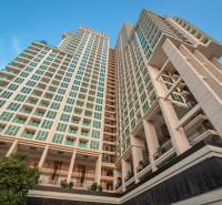 CITY GARDEN TOWER PATTAYA - Výstavba bytov v Pattayi ukazuje vysoké rezidenčné budovy so stromami na pozadí modrej oblohy.