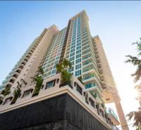 CITY GARDEN TOWER PATTAYA - Výstavba bytov v Pattayi s vysokým mrakodrapom obklopeným palmami a modrou oblohou.