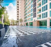 CITY GARDEN TOWER PATTAYA - Výstavba bytov v Pattayi zahŕňa bazén, vysokú budovu a zelené rastliny.