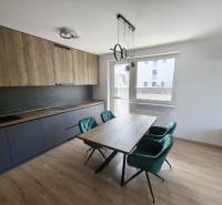 Prenájom 3 izb. byt NOVOSTAVBA, Ivanská cesta, Bratislava II. Ružinov - Kuchyňa v 3-izbovom byte s drevenými a tmavými skrinkami, jedálenský stôl a smaragdové stoličky.