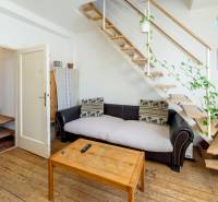Zaujímavý 2i mezonet 65m2, s pavlačou, petfriendly KRÁTKODOBÝ PRENÁJOM - Obývacia izba v 2-izbovom byte so schodiskom, drevenou podlahou a rastlinami.