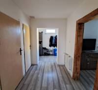 Predáme rodinný dom, pozemok 956 m2, Kmeťovo, okr. Nové Zámky - Chodba v rodinnom dome s laminátovou podlahou, drevenými zárubňami a skladom obuvi.