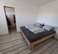 Predáme rodinný dom, pozemok 956 m2, Kmeťovo, okr. Nové Zámky - Spálňa rodinného domu s posteľou, vínovou podlahou a vchodom do komory.