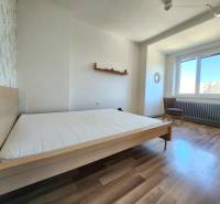- PRENÁJOM - 2-IZBOVÝ BYT - 61 M2 - OBCHODNÁ UL - STARÉ MESTO - Spálňa v 2-izbovom byte s drevenou podlahou, posteľou a kreslom.