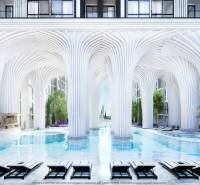 EMBASSY LIFE PATTAYA - Luxusná výstavba bytov s bazénom a bielymi stĺpmi pripomínajúca futuristickú architektúru.