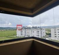 NA Predaj 4 izbový byt v projekte VINICE Pezinok 150m2 - Výhľad z balkóna 4-izbového bytu na zelené polia a okolité budovy v Pezinku.