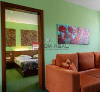 PREDAJ B&B Hotel v Starom meste - škola, centrum medicíny - Interiér penziónu s oranžovou sedačkou, obrazmi a posteľou s pestrými prikrývkami.