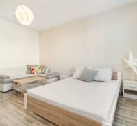PRI ELEKTRIČKE - 1 izb. 36,20 m2 - oddelená kuchyňa - Osuského ul. - Svetlá izba s posteľou, sedačkou a ventilátorom v 1-izbovom byte.