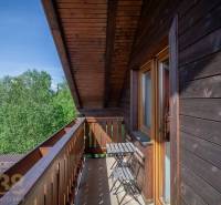 Znížená cena: priestranný apartmán s TOP polohou v Starom Smokovci - Balkón so stolom a stoličkami v Rekreačnom apartmáne s výhľadom na stromy vo Vysokých Tatrách.