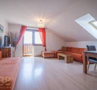 Znížená cena: priestranný apartmán s TOP polohou v Starom Smokovci - Rekreačný apartmán s oranžovou sedacou súpravou a jedálenským stolom pod strešným oknom.