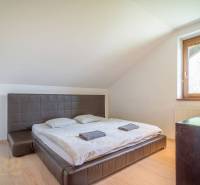 Znížená cena: priestranný apartmán s TOP polohou v Starom Smokovci - Spálňa v Rekreačnom apartmáne s dvojposteľou, oknom, dreveným nábytkom a strešnými sklony.