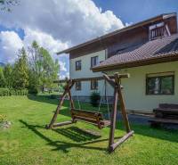 Znížená cena: priestranný apartmán s TOP polohou v Starom Smokovci - Záhrada s drevenou hojdačkou a lavičkou pri Rekreačnom apartmáne vo Vysokých Tatrách.