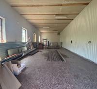 Na prenájom hala s pozemkom 4500 m² – Mníchova Lehota  - Interiér haly so skladovými materiálmi a oknami na jednej strane.