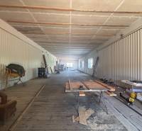 Na prenájom hala s pozemkom 4500 m² – Mníchova Lehota  - Priestranný interiér skladov a hál s drevenou podlahou, stavebným materiálom a náradím.