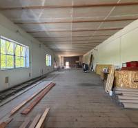 Na prenájom hala s pozemkom 4500 m² – Mníchova Lehota  - Interiér skladov a hál s drevenou podlahou, regálmi a stavebným materiálom.
