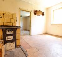 Starší rodinný dom – Ihrište_Púchov  - Kuchyňa v rodinnom dome s kachľovou pecou a drevenou podlahou.