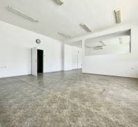 Kancelárie na prenájom 60m2, budova Fischer TireTech, TN - Priestranné kancelárie s bielymi stenami, podlaha z dlažby, dvere, hodiny na stene.