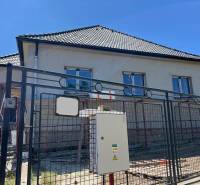 4iz RD Sasinkovo - Rodinný dom v Sasinkove na ulici Sasinkovo s nedokončenou fasádou za kovovým plotom.