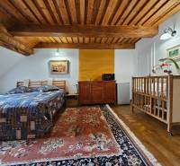 PREDAJ - Rodinný dom na Donovaloch s 3 samostatnými apartmánmi - Spálňa v rodinnom dome s dreveným stropom, posteľou, detskou postieľkou a kobercom.