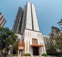ONCE PATTAYA - Výstavba bytov v Pattayi, vysoká budova s modernou architektúrou a zeleňou okolo.
