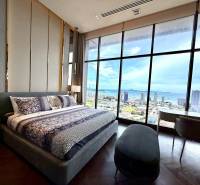 PENTHOUSE ONCE PATTAYA - Spálňa v 4-izbovom byte s veľkým oknom ponúka výhľad na mesto a pobrežie.