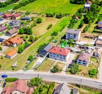 Na predaj 2-izbový byt so záhradkou a garážou! - Letecký pohľad na domy v Púchove s okolitou zeleňou a cestnou infraštruktúrou.