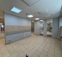 Prenájom obchodného priestoru v OD Prior v širšom centre Popradu - Prázdne obchodné priestory s dlažbou, veľkými zrkadlami a osvetlením na strope.