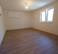 Na predaj zrekonštruovaný rodinný dom - Trakovice - Prázdna miestnosť s laminátovou podlahou a bielymi stenami v rodinnom dome.