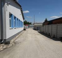Skladová hala na prenájom 108 m², novostavba | Tureň - Plocha medzi budovami, Sklady a haly v Tureň, betónový povrch, modré okná.