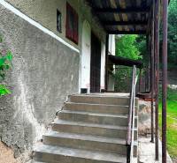 STARŠÍ RODINNÝ DOM, POZEMOK 2476 m2, VEĽKÁ LESNÁ; - Vchod so schodiskom do rodinného domu vo Veľkej Lesnej, obklopený zelenou vegetáciou.