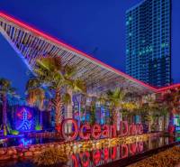 THE RIVIERA OCEAN DRIVE PATTAYA - Nočná scéna s osvetlenou budovou a nápisom v rámci výstavby bytov v Pattaye.