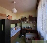 Priestranný poschodový rodinný dom v Lovinobani - Izba v rodinnom dome s posteľou, stolom a regálom.