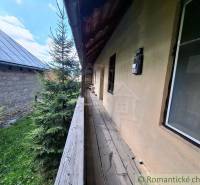 Súbor nehnuteľností určených na revitalizáciu Pohorelá -Nízke Tatry - Drevený chodník vedľa rodinného domu v Pohorelej, obklopený zeleňou a susednou budovou.
