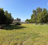 Predaj, pozemok pre rodinný dom   3788 m2 Veľký Mede... - Zelený pozemok určený na bývanie vo Veľkom Mederi, obklopený stromami a trávou.