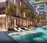 THE RIVIERA BEVERLY HILLS RESIDENCES PATTAYA - Výstavba bytov v Pattayi s bazénom a ležadlami obklopenými palmami a rastlinami.