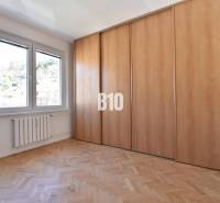 Predaj 4-izbového bytu, Kuzmányho, Kuzmányho, Považská Bystrica - Izba v 4-izbovom byte s drevenou podlahou, vstavanou skriňou a výhľadom do exteriéru.