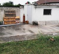 Predaj rodinného domu, Neusiedl am See - Dvor pri rodinnom dome v 2473 Potzneusiedl s betónovou plochou a drevenými paletami.