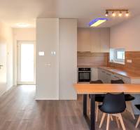 4-izbový dvojdom s terasou pre rodiny v pokojnej zóne | 97m² - Kuchyňa s jedálenským stolom v rodinnom dome, s drevenými obkladmi a vstavanou rúrou.