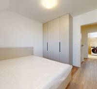 4-izbový dvojdom s terasou pre rodiny v pokojnej zóne | 97m² - Spálňa v rodinnom dome s posteľou, skriňou a pohľadom na práčku v kúpeľni.